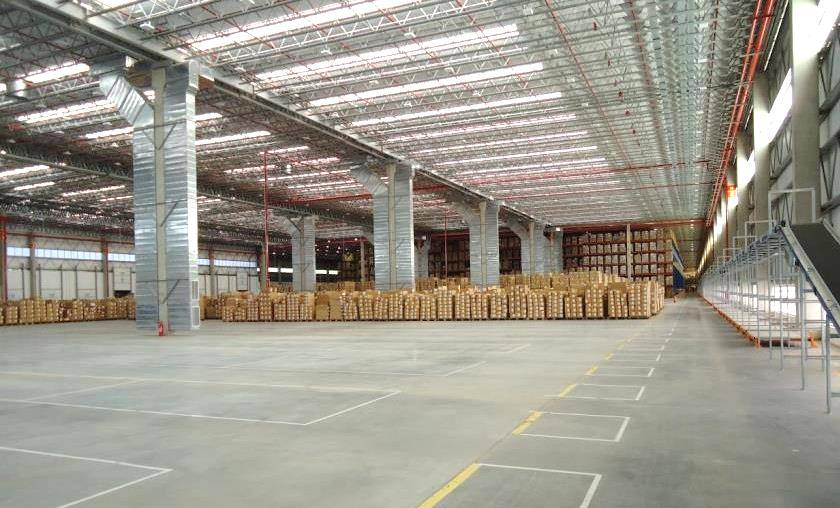 Interior do centro de distribuição da Adidas em Embu/SP, com paletes de caixas e estrutura metálica do galpão