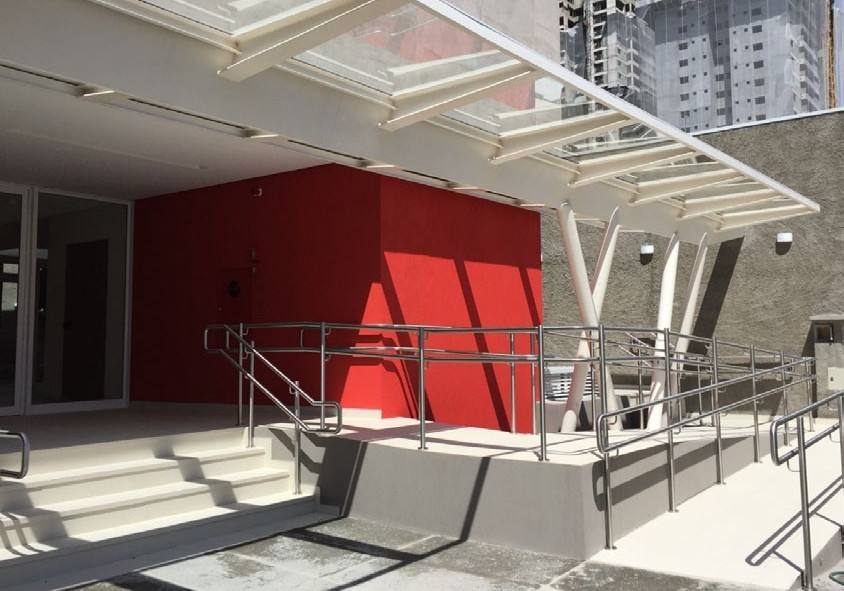 Entrada de unidade da Cultura Inglesa em São Paulo, com parede vermelha e cobertura de vidro.