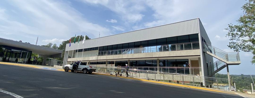 Fachada do novo prédio administrativo da Klabin em Telêmaco Borba/PR, com mastros de bandeiras e portaria ao fundo